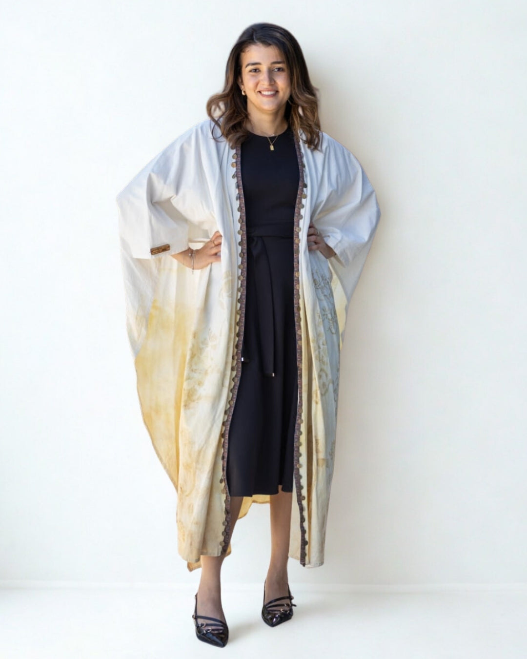 Woman wearing a long, light-colored coat with a white background