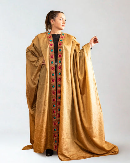 Woman wearing a gold embroidered abaya on a white background
