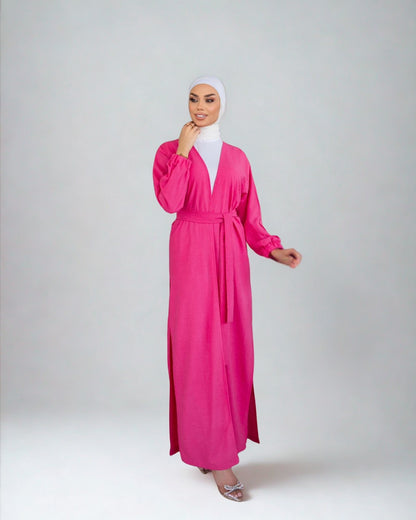 Woman wearing a bright pink dress with a white hijab on a light gray background