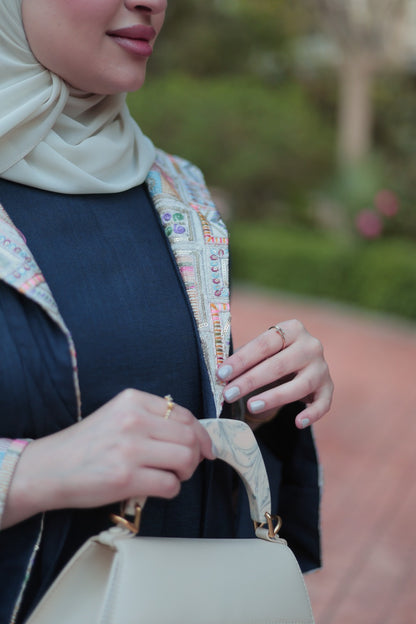 Woman holding a beige handbag with a blurred outdoor background