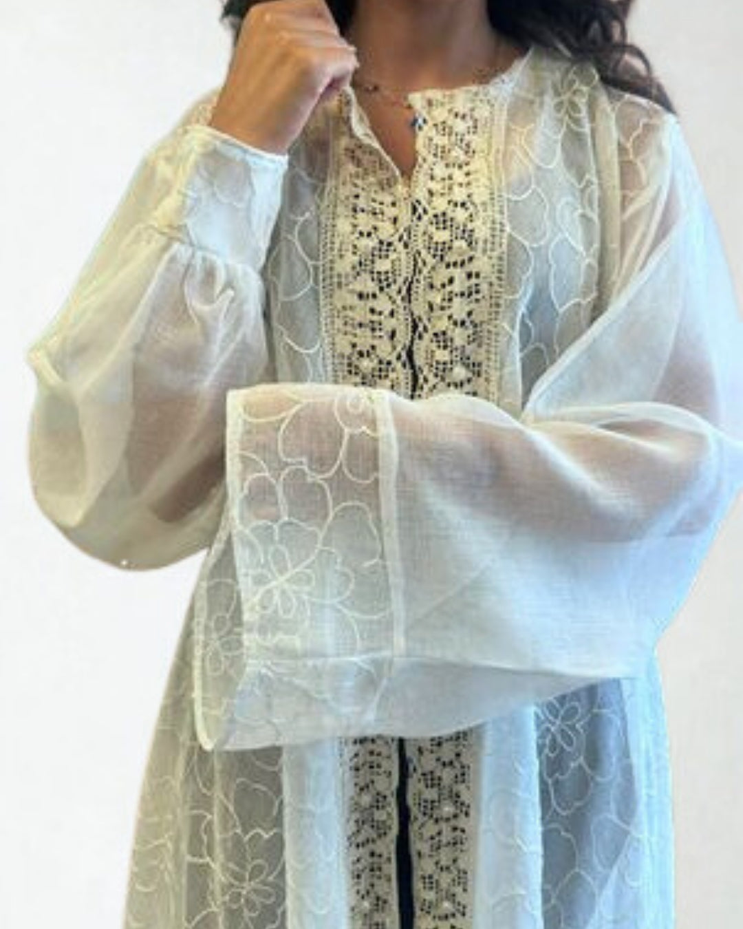 White lace garment with black embroidery on a plain background
