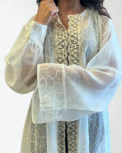 White lace garment with black embroidery on a plain background