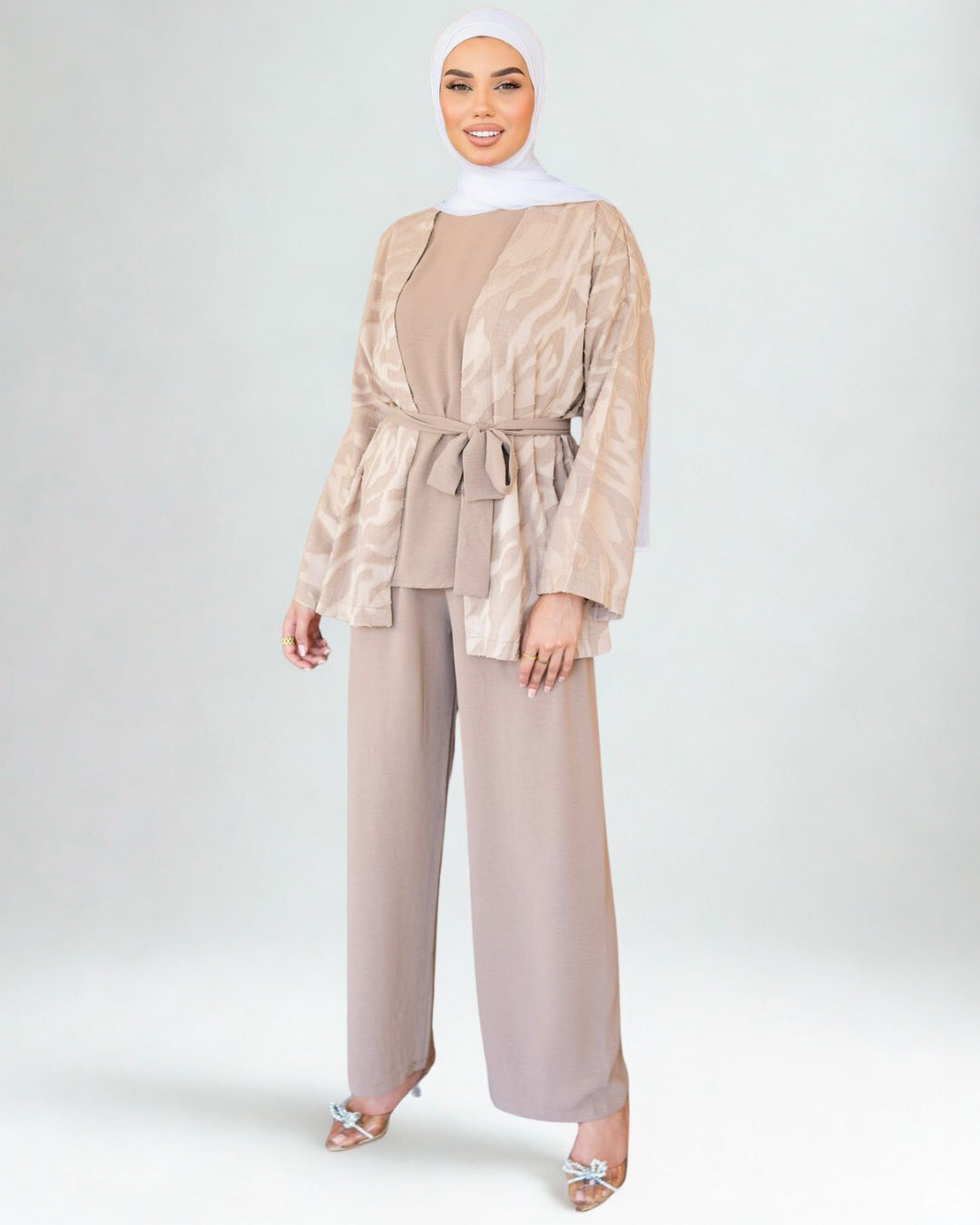 Woman wearing a beige outfit with a matching hijab on a white background