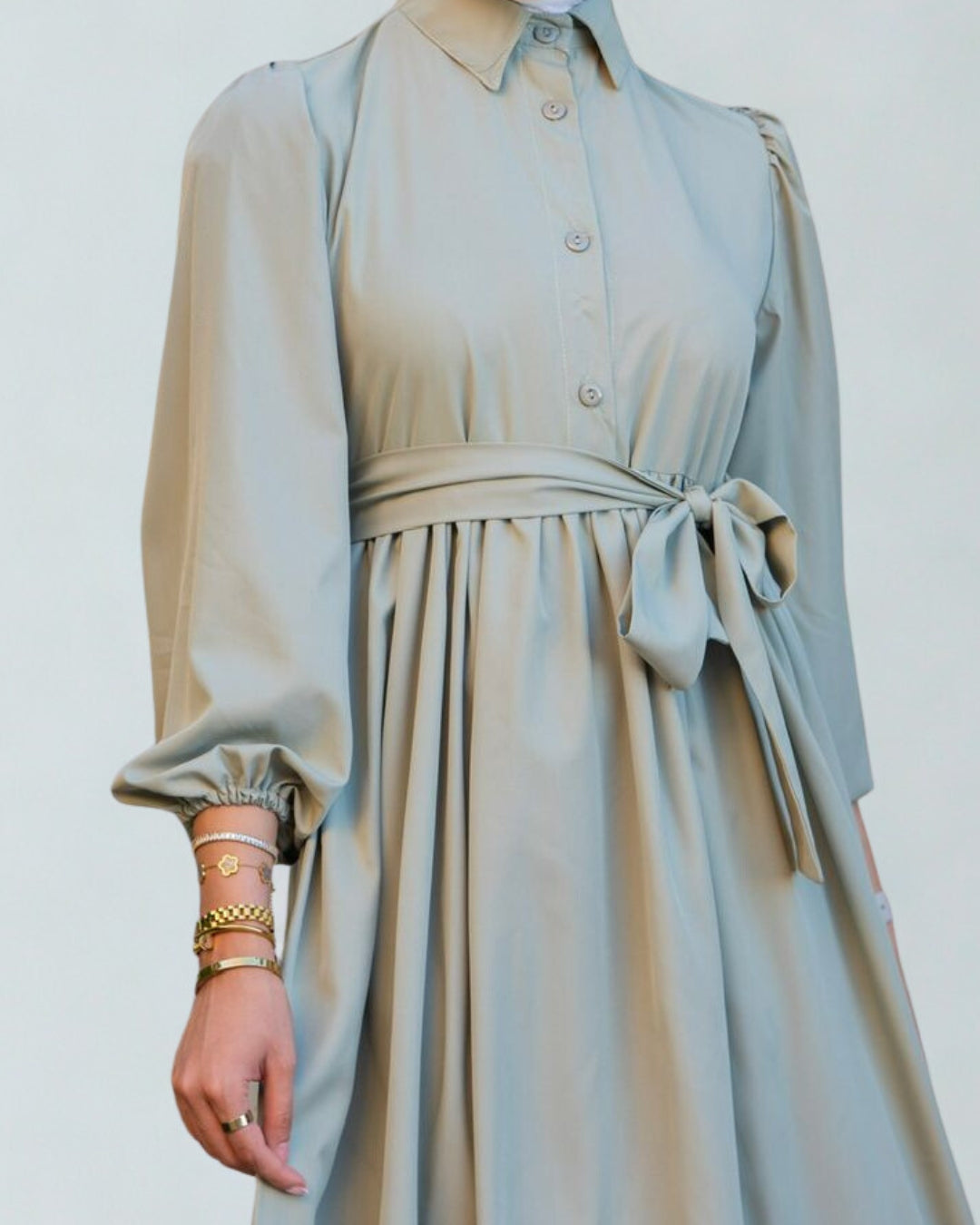 Light blue dress with long sleeves and a belt on a white background