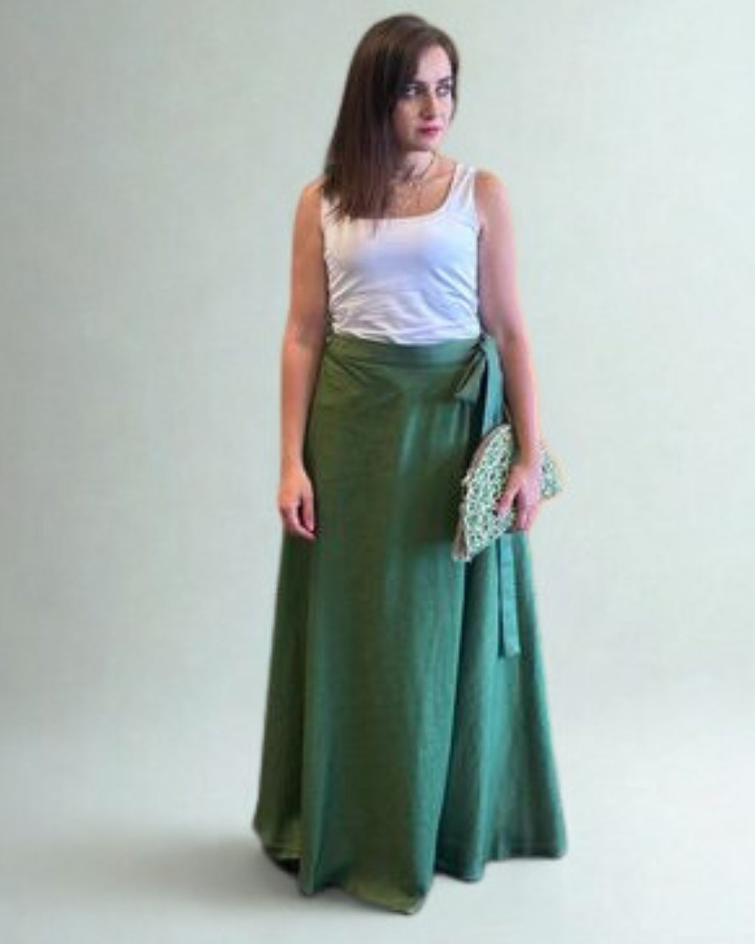 Woman wearing a white top and green skirt on a plain background