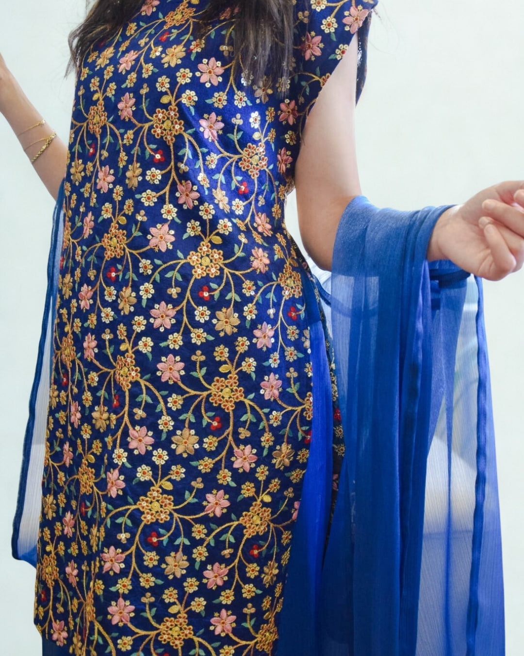 Woman wearing a blue floral dress with a matching scarf against a white background