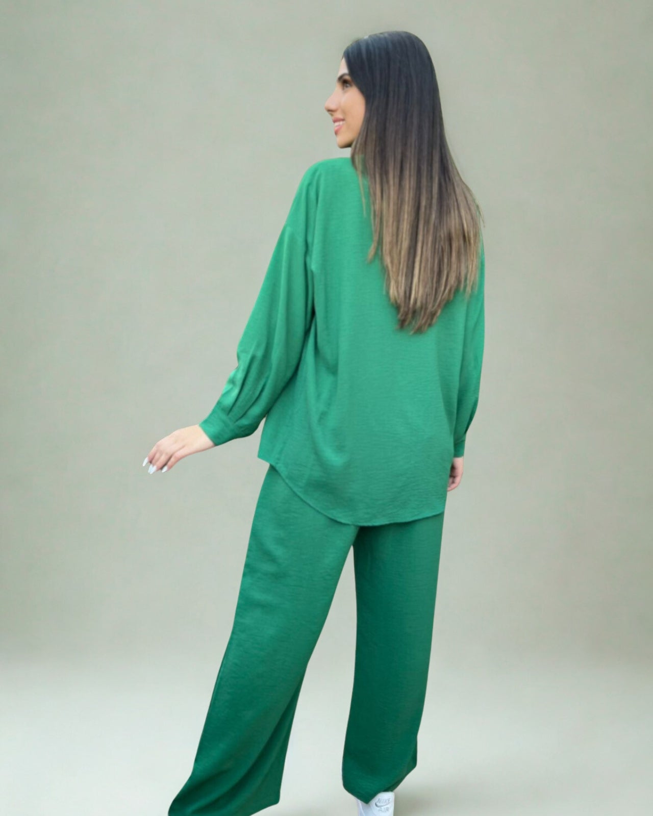 Woman wearing a green outfit against a plain background
