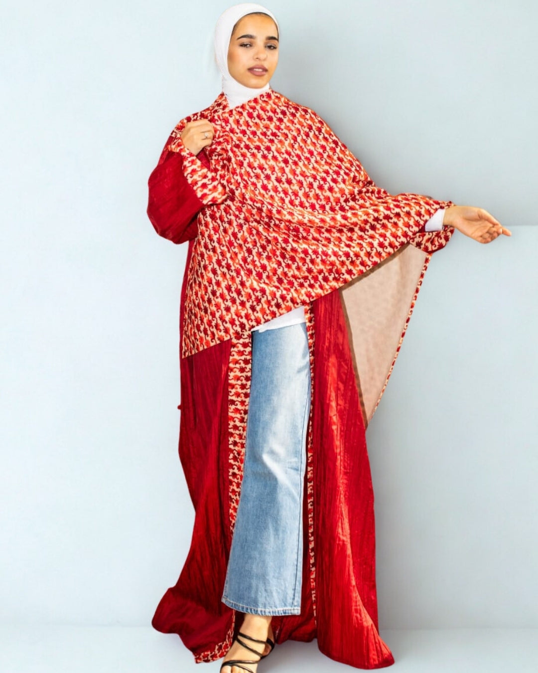 Person wearing a red and white patterned outfit with a hijab on a light gray background