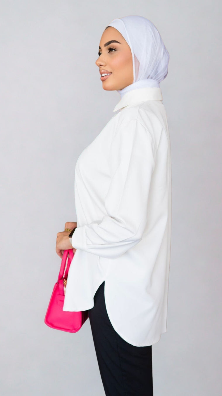 Woman wearing a white hijab and holding a pink bag against a gray background
