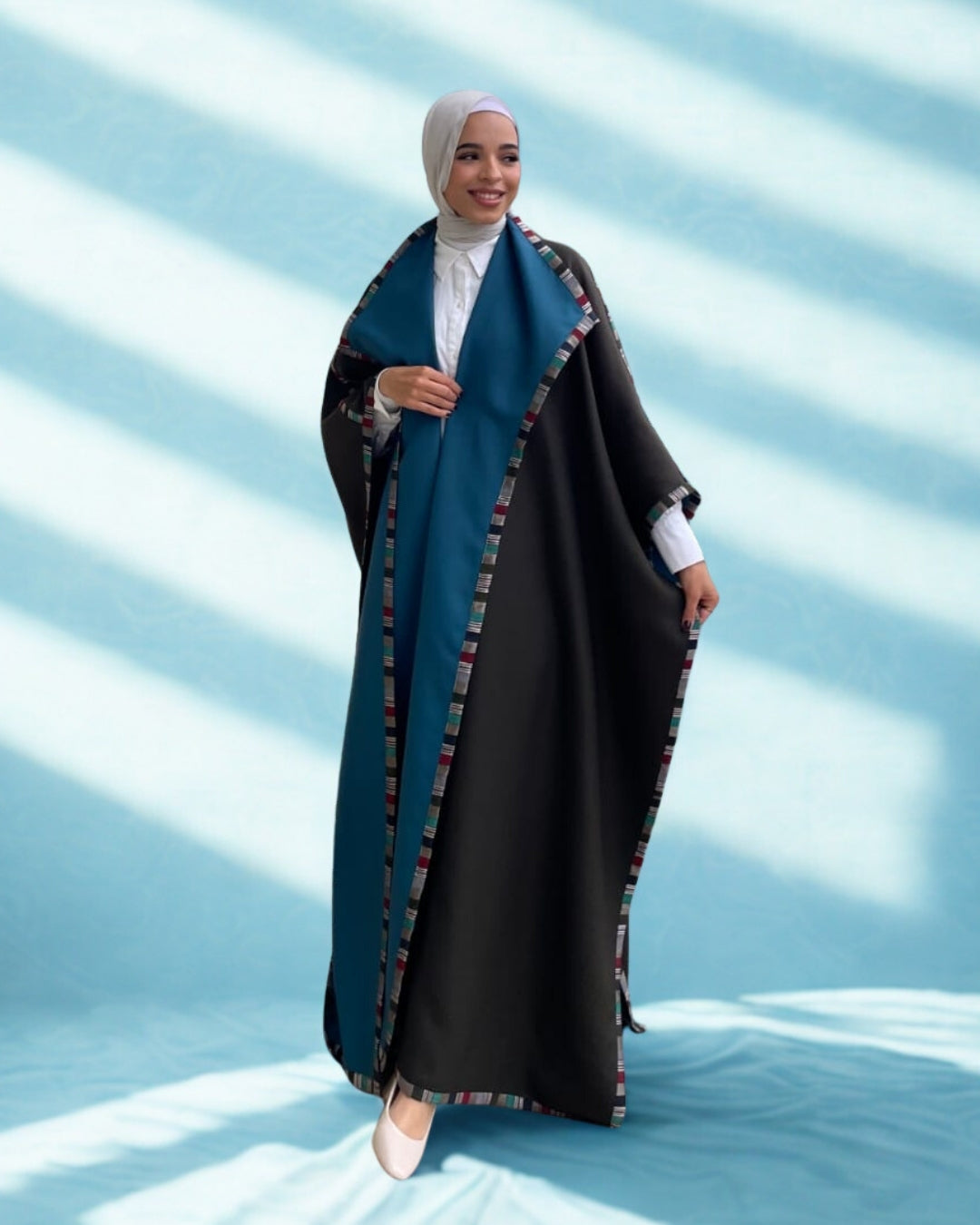 Woman wearing a black and blue abaya with a white background