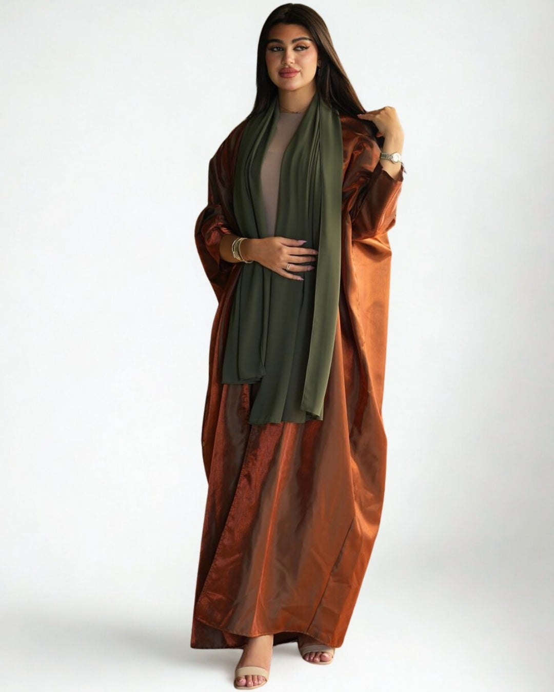 Woman wearing a long, flowing dress with a green top and brown skirt on a white background