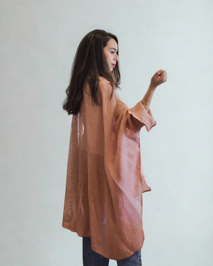 Woman wearing a long, light brown garment against a plain background
