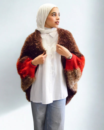 Woman wearing a colorful fur coat over a white shirt with a plain background