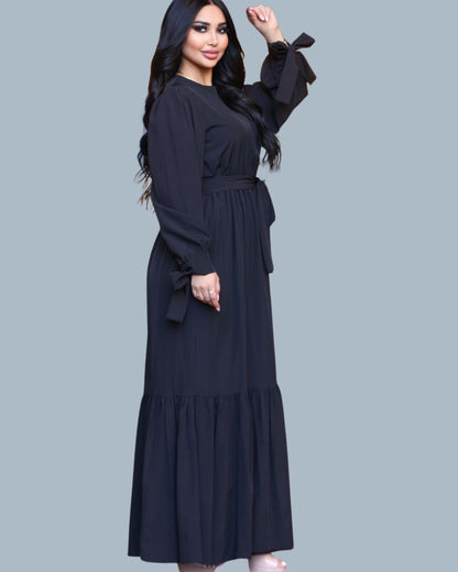 Woman wearing a black long-sleeve dress with a plain background