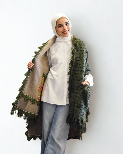 Woman wearing a green textured scarf over a white top and light blue pants on a white background