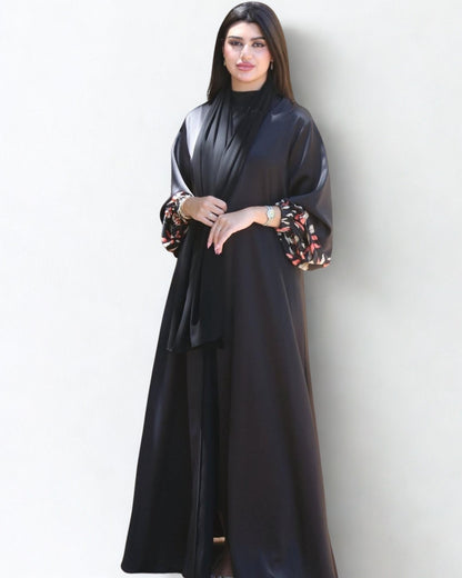 Woman wearing a black abaya with floral sleeves against a white background