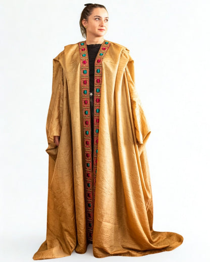 Woman wearing a long, gold embroidered dress on a white background