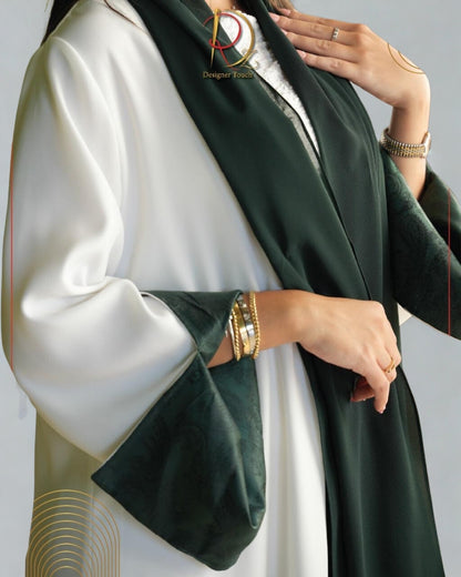 Person wearing a white outfit with a green scarf, gold jewelry, and a logo in the corner.