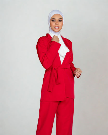 Person wearing a red outfit with a white hijab on a plain background