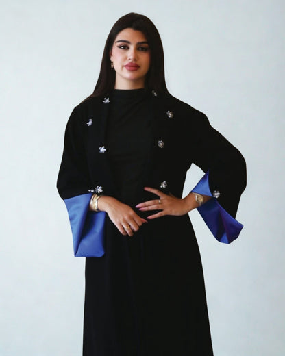 Woman wearing a black dress with blue sleeves against a white background