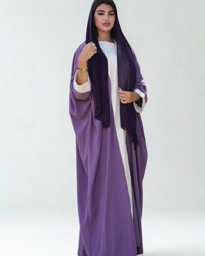 Woman wearing a long purple dress with a white top on a white background