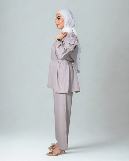 Woman wearing a light gray outfit with a matching hijab on a white background