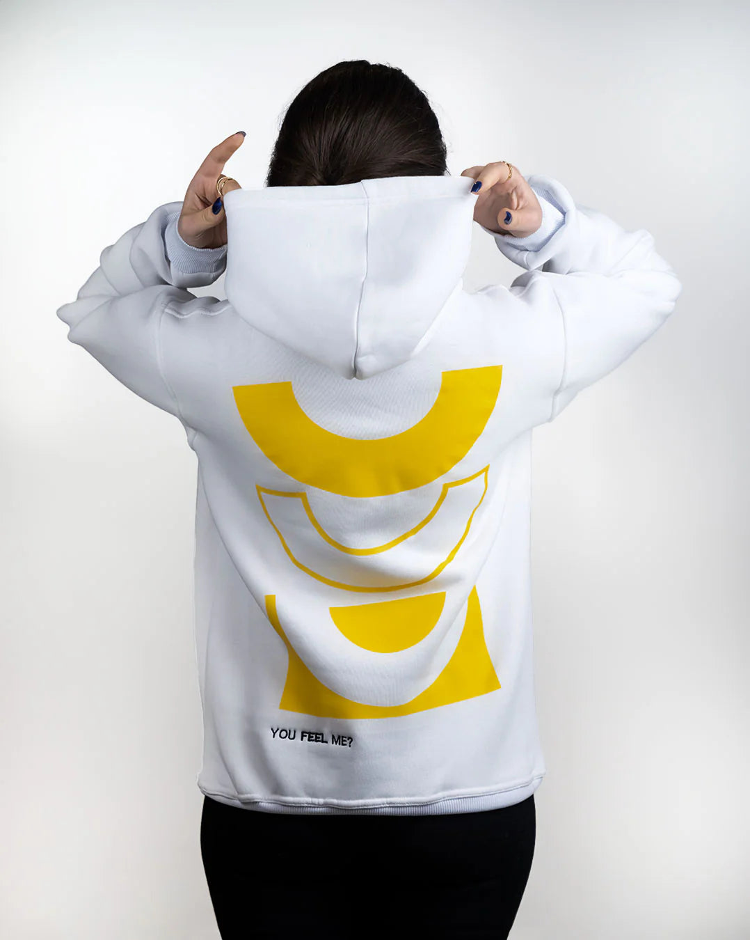 Person wearing a white hoodie with a yellow logo on the back against a plain background