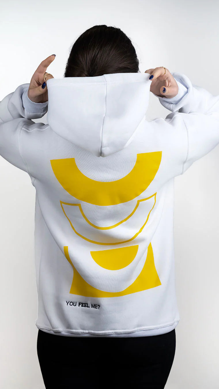 Person wearing a white hoodie with a yellow logo on the back against a plain background