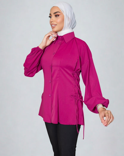 Woman wearing a bright pink blouse with long sleeves on a plain background