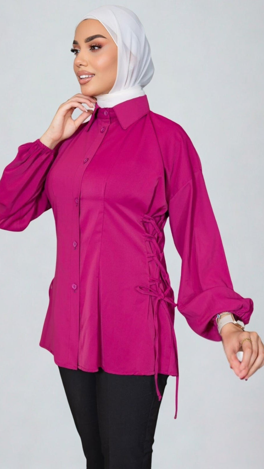 Woman wearing a bright pink blouse with long sleeves on a plain background