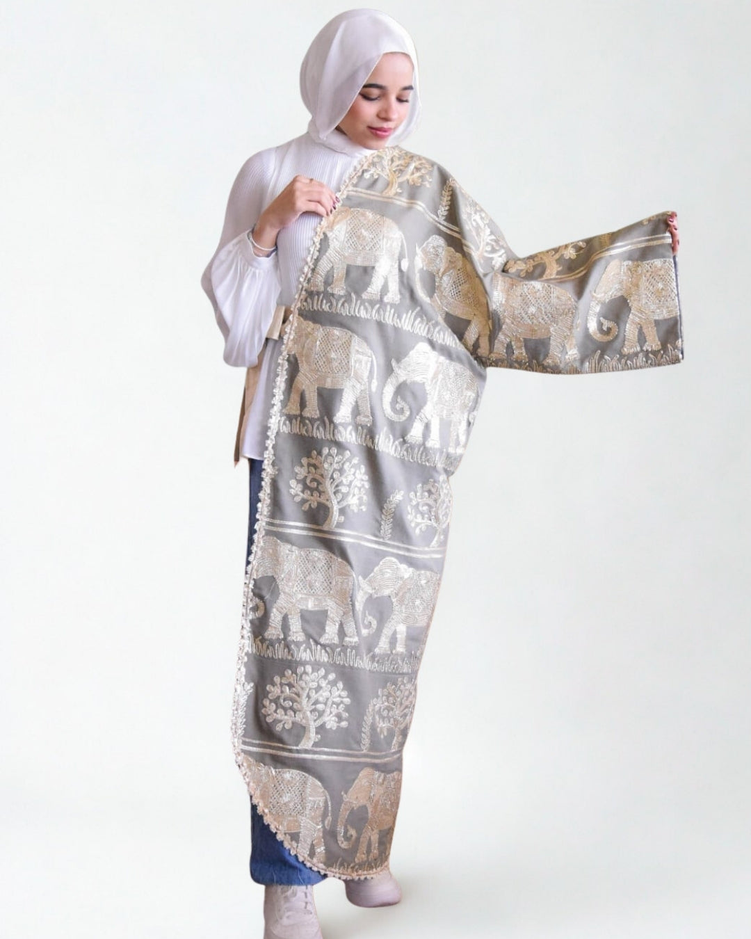 Woman holding a large patterned scarf with elephants on a white background