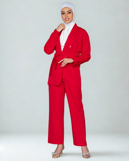 Woman wearing a red suit with a white hijab on a light gray background