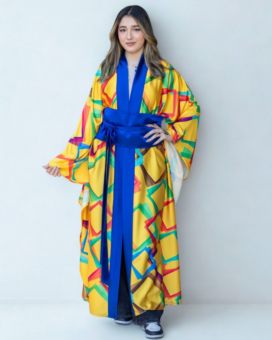 Woman wearing a colorful kimono with a blue belt against a white background