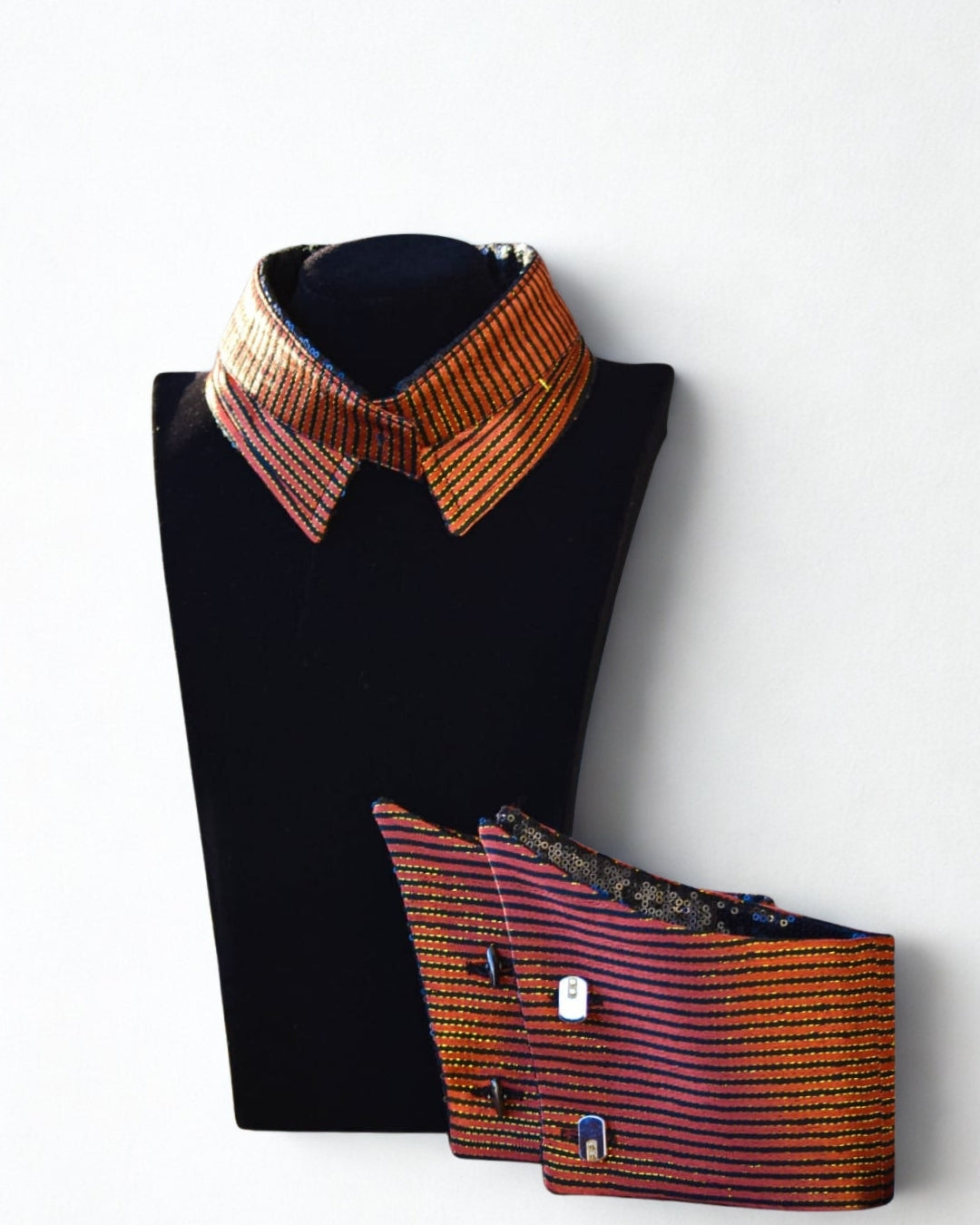 Black mannequin with a colorful striped collar and matching waistcoat on a white background