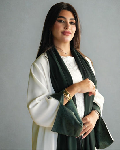 Woman wearing a white outfit with a dark green scarf against a gray background