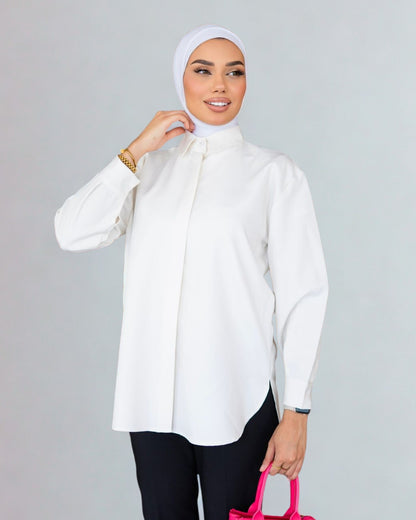 Woman wearing a white blouse and hijab with a pink bag on a gray background