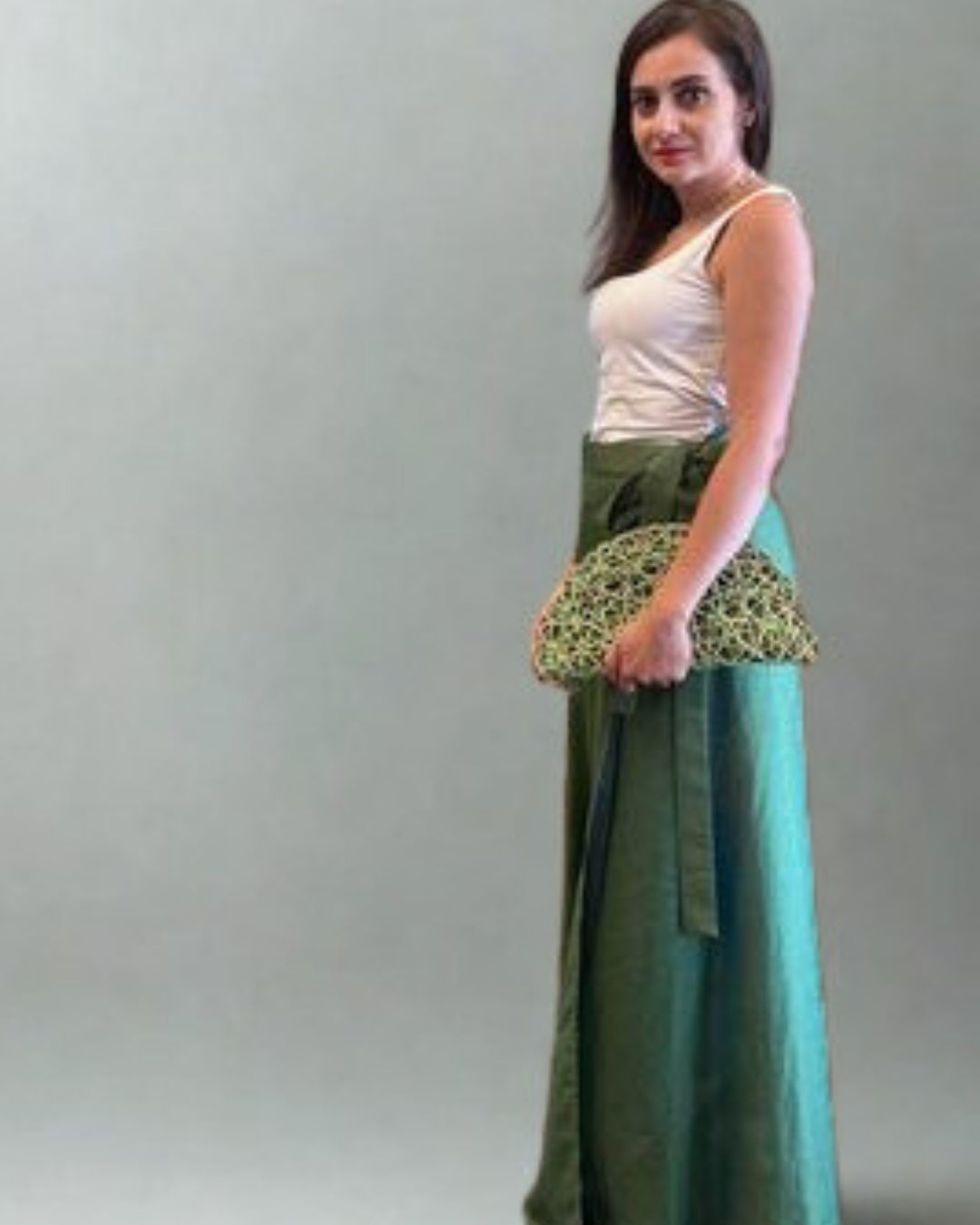 Woman wearing a green skirt with a patterned top against a plain background