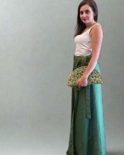 Woman wearing a green skirt with a patterned top against a plain background