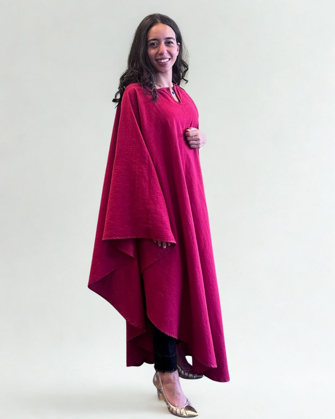 Woman wearing a bright pink dress with a draped design against a white background