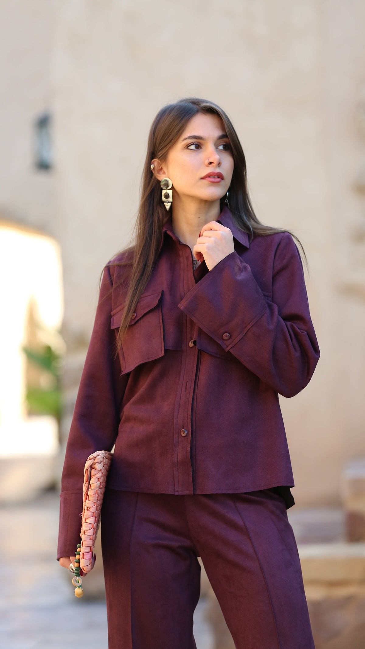 Woman in a purple outfit posing indoors with a blurred background
