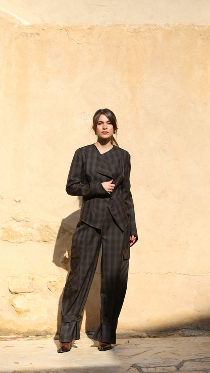 Woman in a black outfit standing against a beige stone wall.