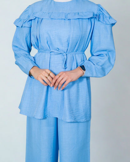 Light blue outfit with ruffled top and wide-leg pants on a plain background