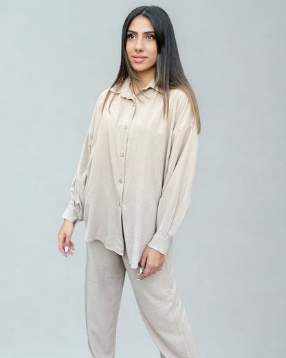 Woman wearing a beige shirt and pants set against a plain background