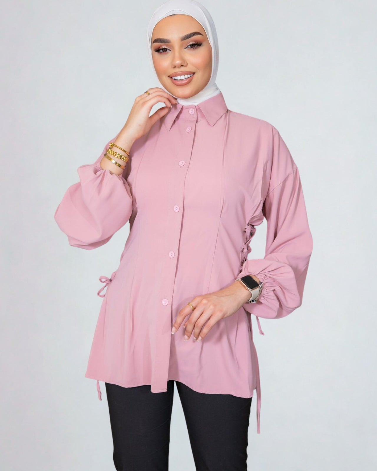 Woman wearing a pink blouse with long sleeves on a white background