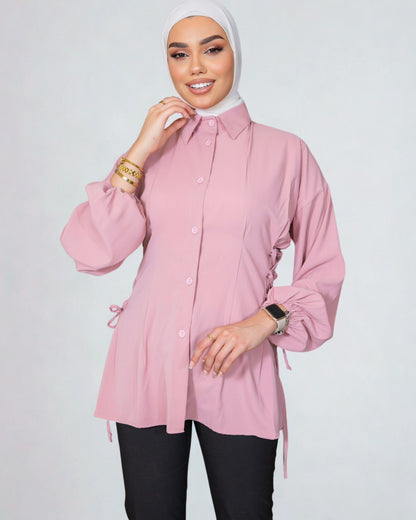 Woman wearing a pink blouse with long sleeves on a white background