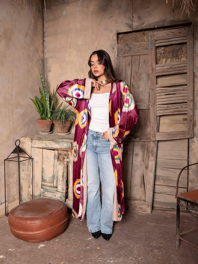 Woman wearing a colorful kimono-style jacket in a rustic indoor setting.