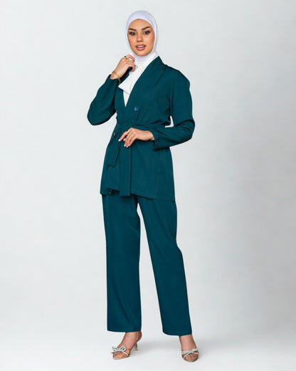 Woman wearing a teal suit with a white hijab on a white background