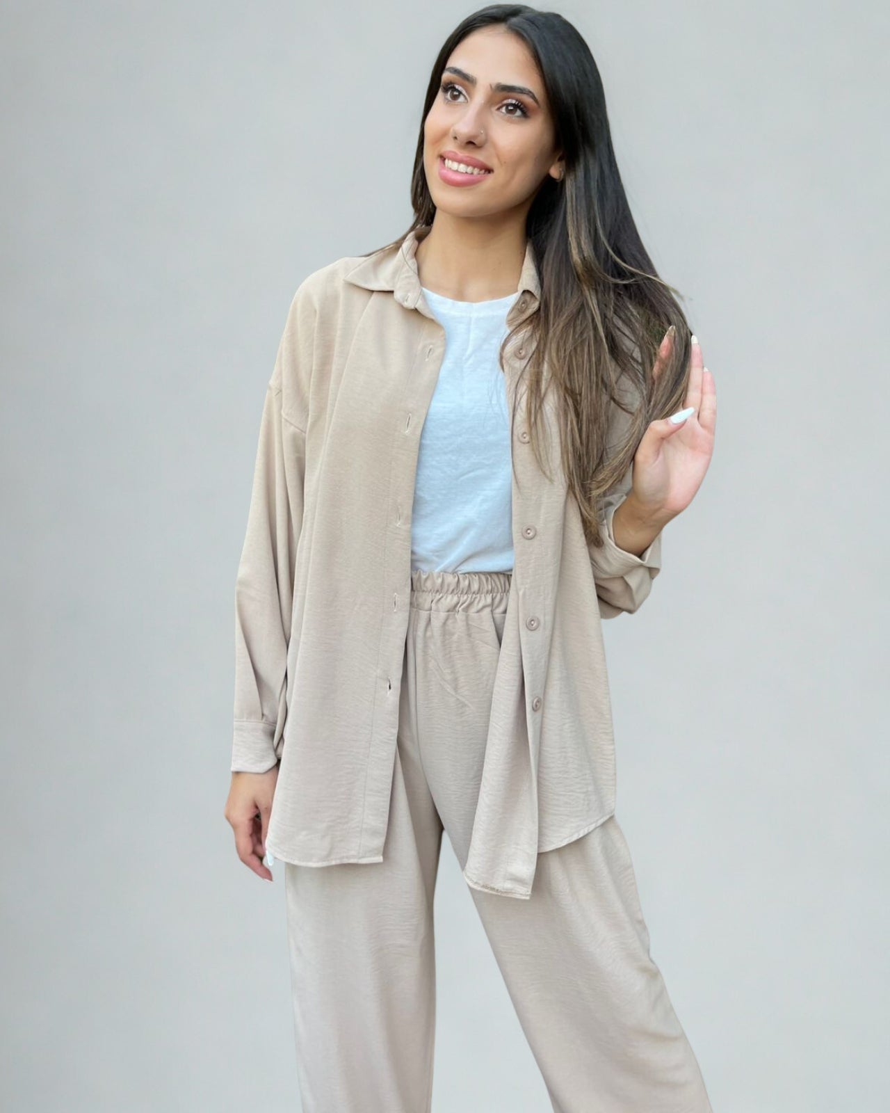 Woman wearing a beige shirt and pants set against a plain background
