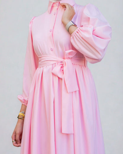 Pink dress with a belt on a plain background