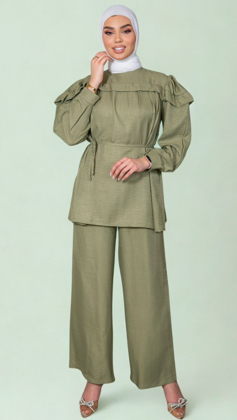 Woman wearing a green outfit with a matching hijab on a light green background